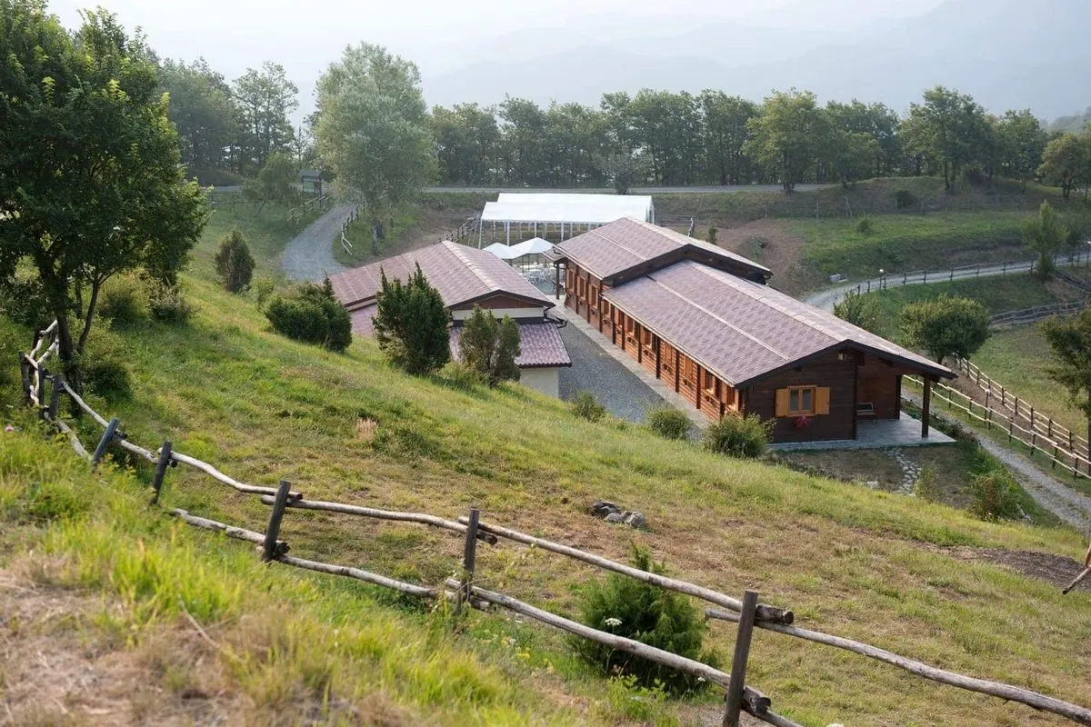 Pian della Castagna d'estate: le case di legno sul prato, tra gli alberi e le colline